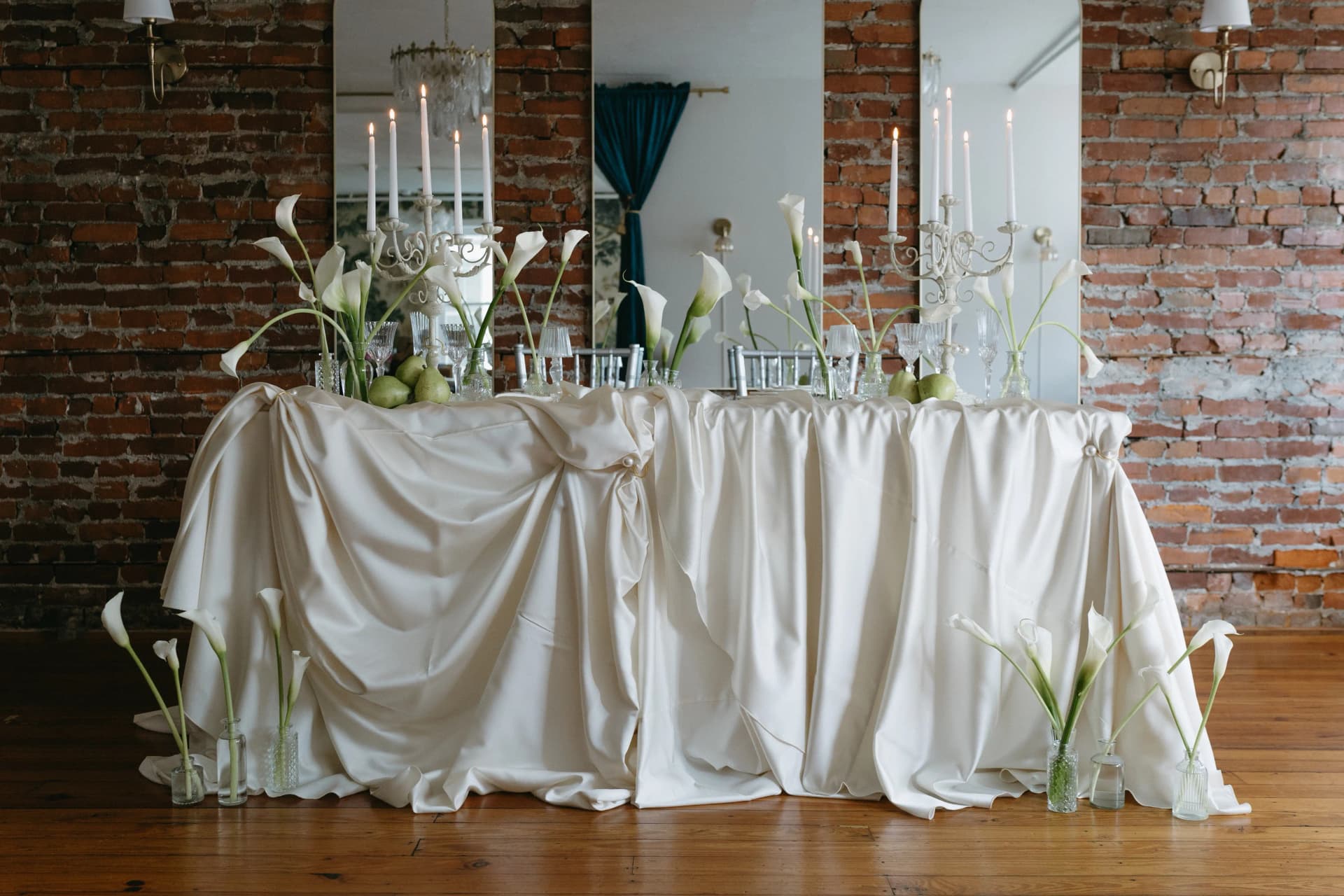 A table with white tablecloth, calla lilies, and candles