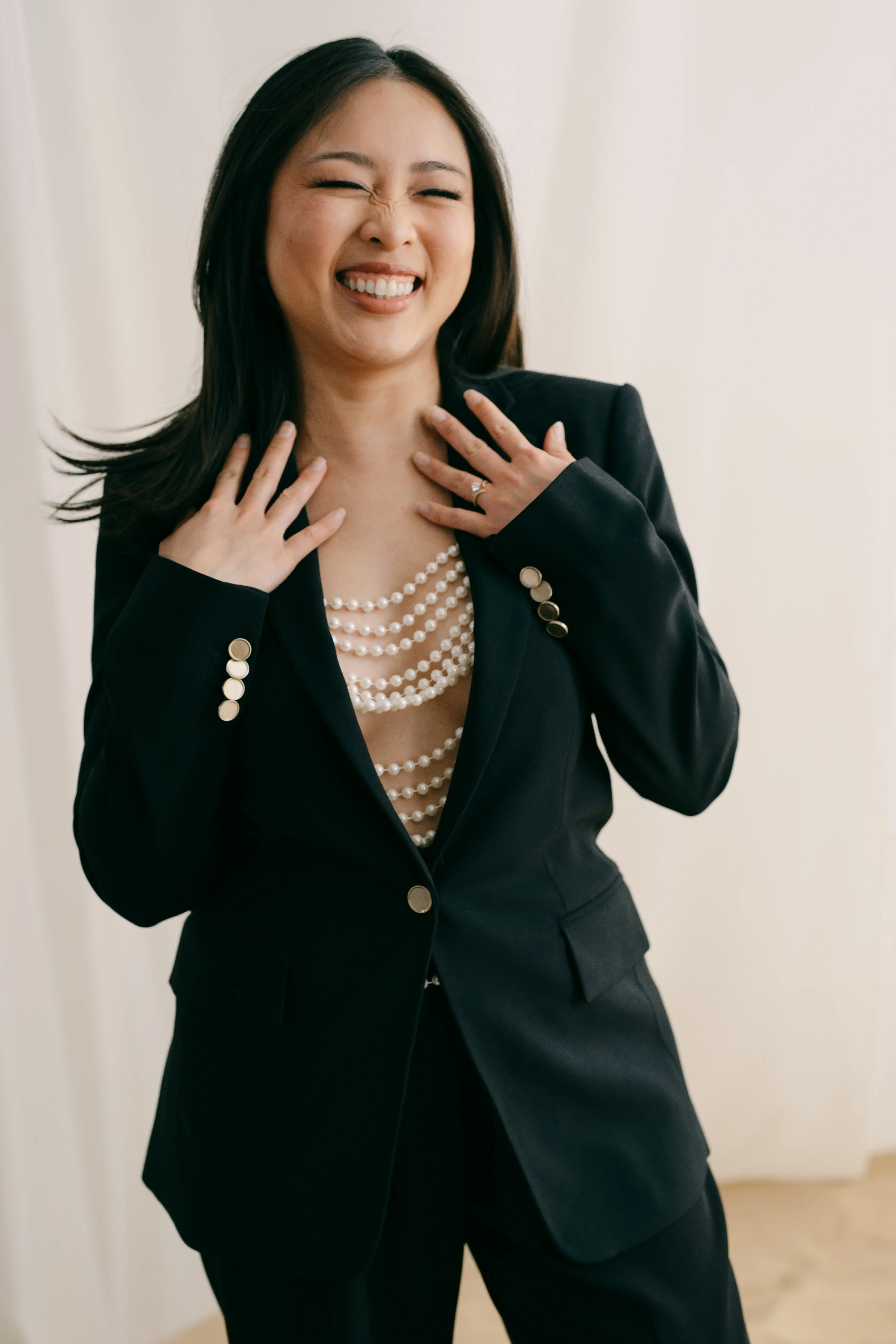 San Le, founder of Vivid Moments with San, laughing in a black suit and pearls