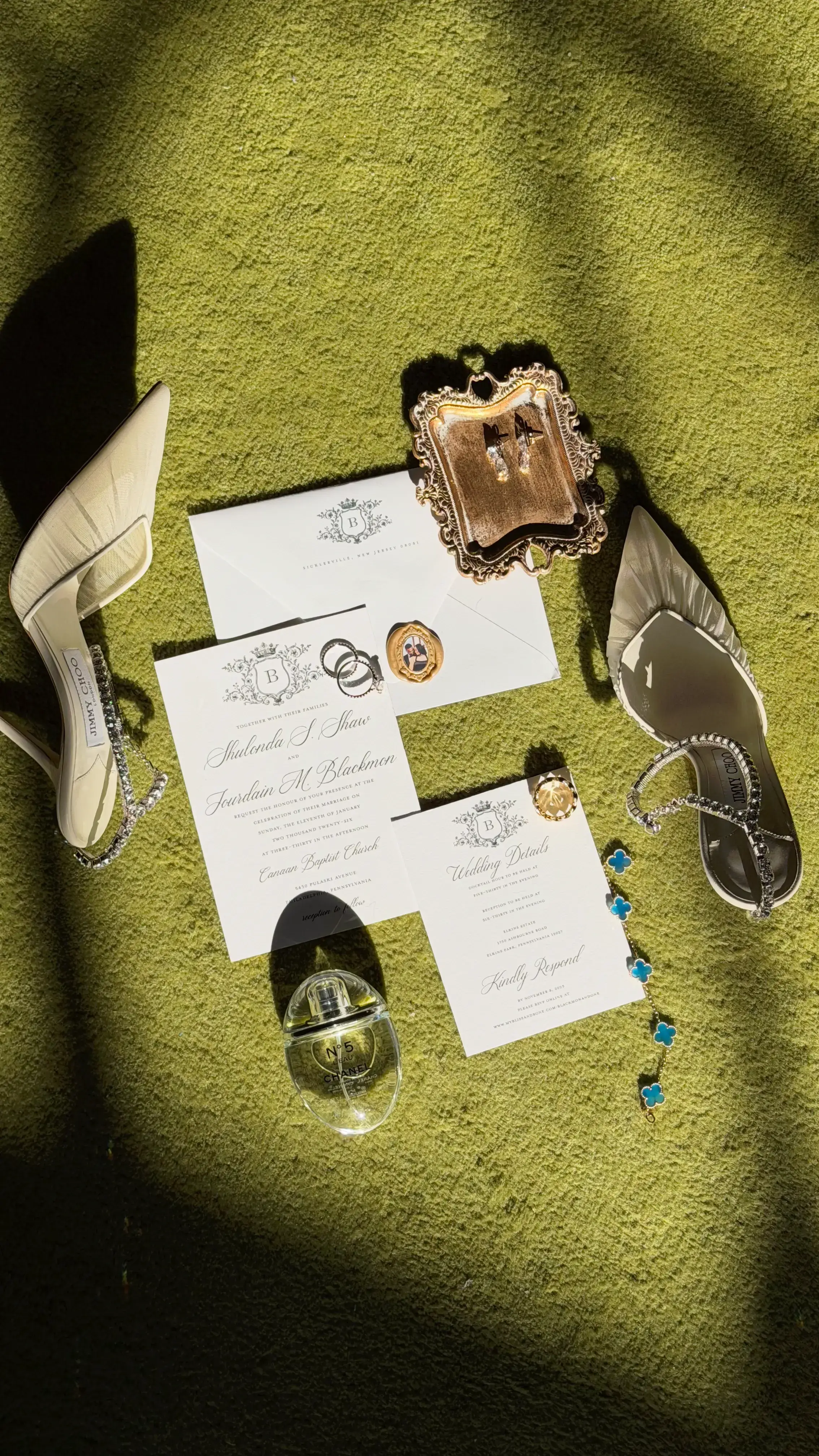 An invitation suite, rings and jewellery laid out on moss green velvet