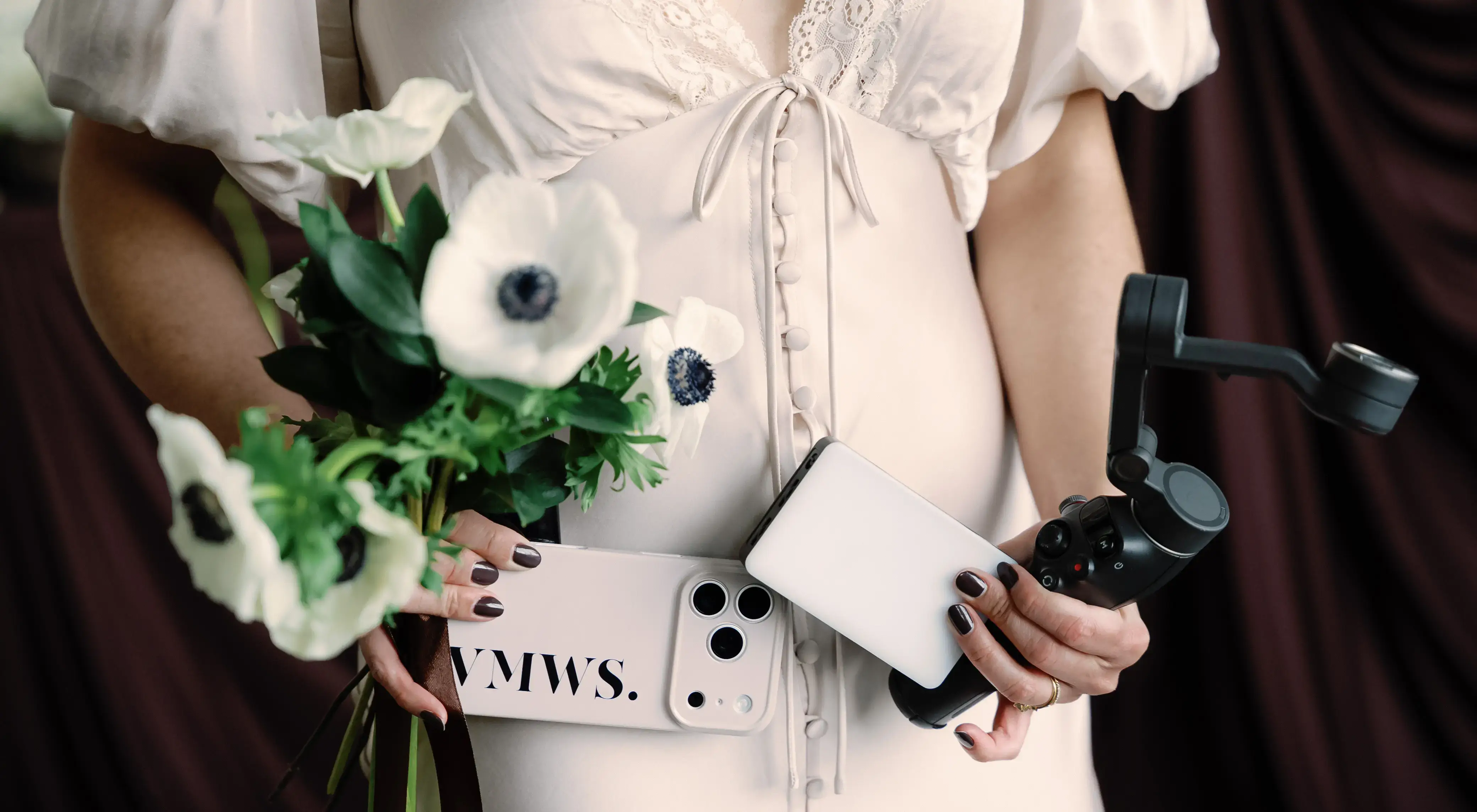 A girl in a cream dress holding white anemones and a phone in a VMWS case